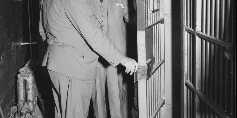 archival photo of two men surveying a prison cell